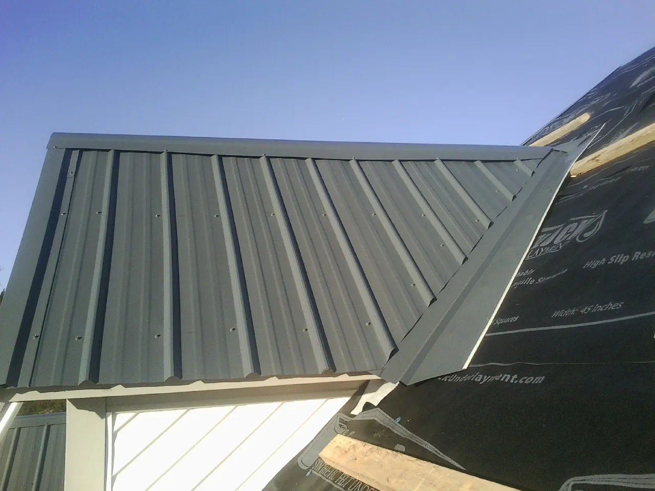 Gray metal roof panels going on over a garage gable in Elk Creek