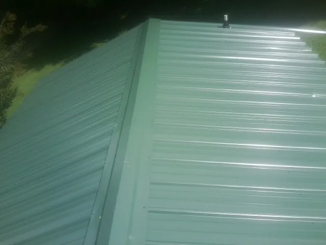 New green metal panels meeting at the ridge of a roof — Flat Roof Repair work by our crew in Elk Creek