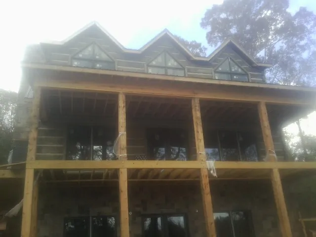 Dormers and porch framing on a large log home under construction — Roof Coating work by our crew in Elk Creek