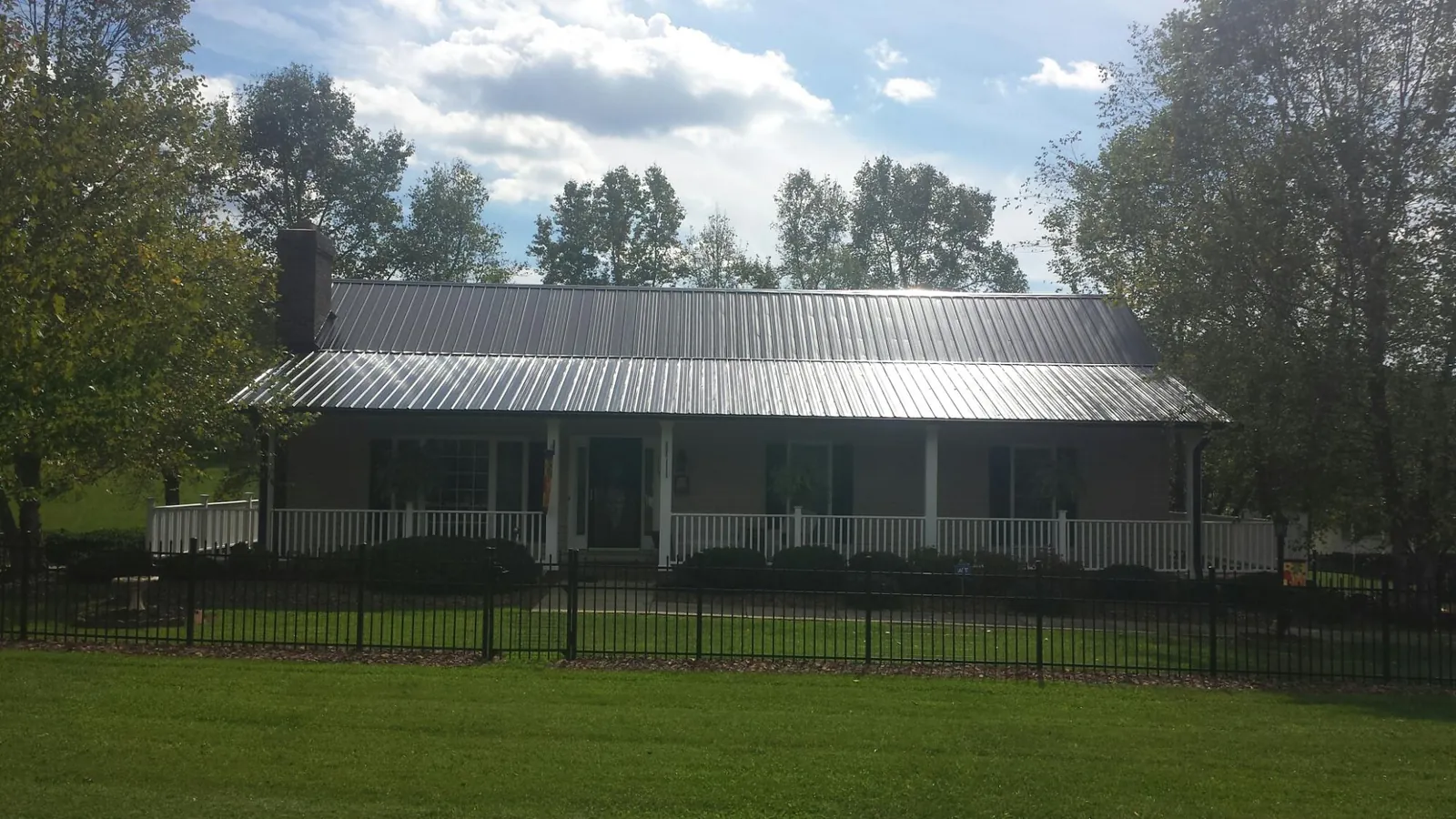 Gray metal roof on a brick ranch with a full width front porch — Gutter Guard Installation work by our crew in Elk Creek