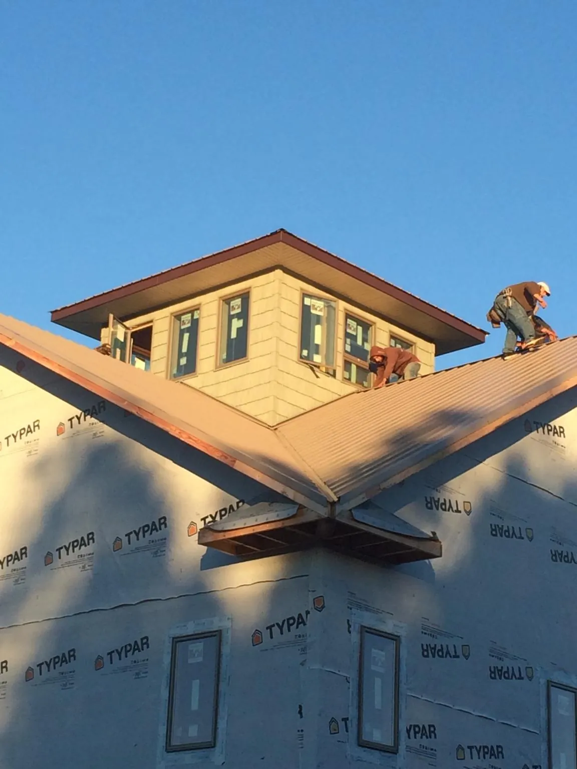 Roofers working around a rooftop cupola on a new metal roof at sunset — Roof Waterproofing in Elk Creek by Roofing Brothers